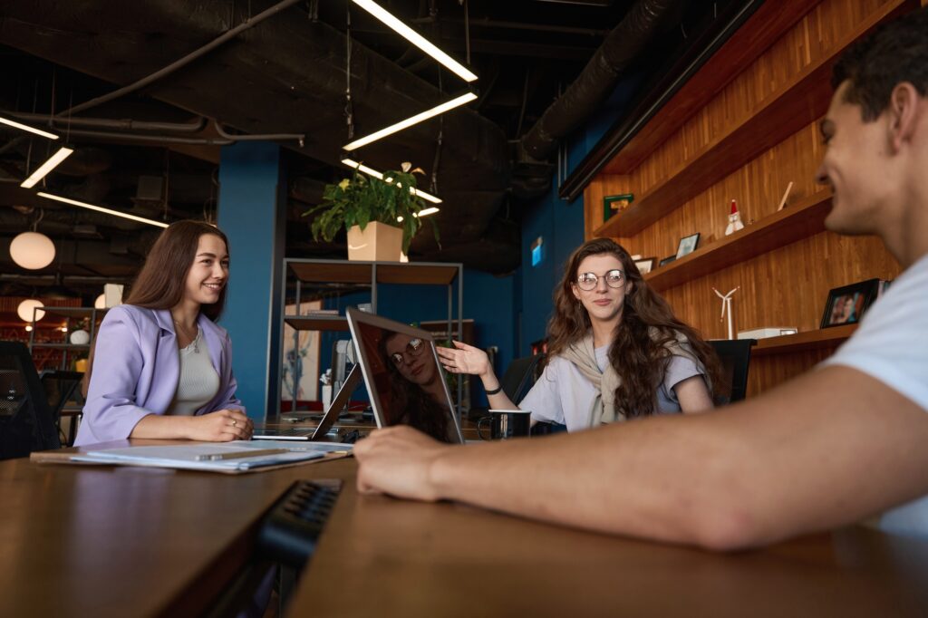 Team collaboration at a coworking space in Washington DC. Coworkers collaborating on a project using a laptop. Business meeting at a shared office.