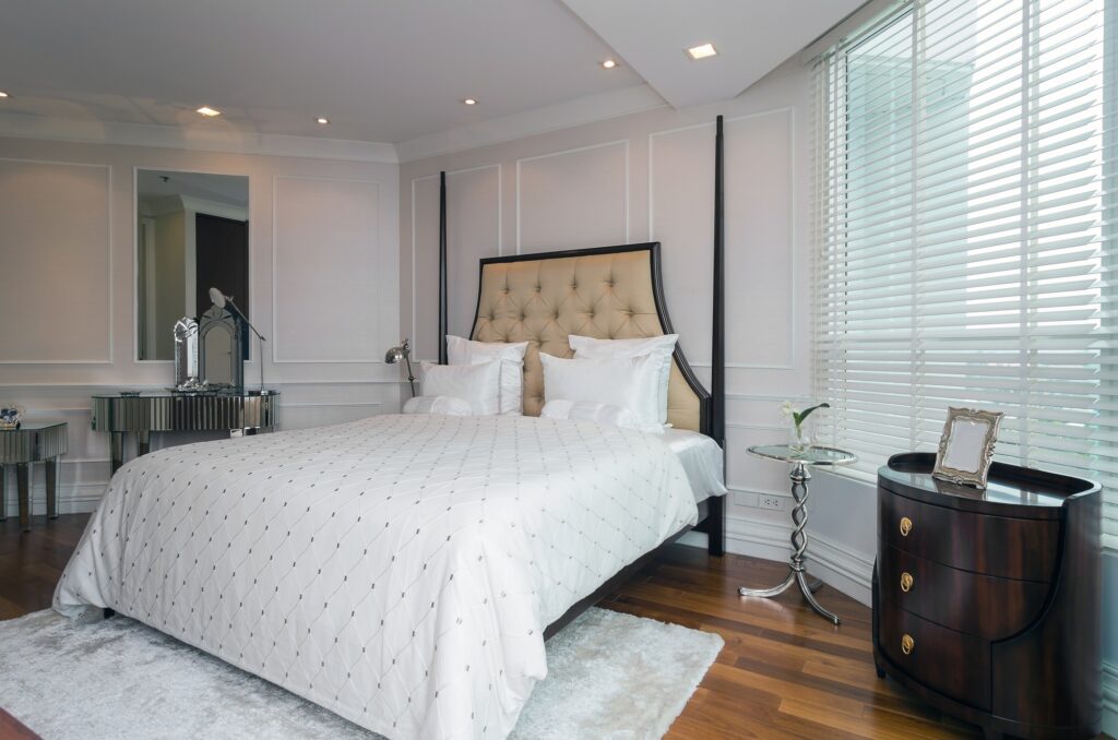 Bedroom interior design with a large bed, white bedding, and a wooden floor. Interior design in Washington DC with a modern style.