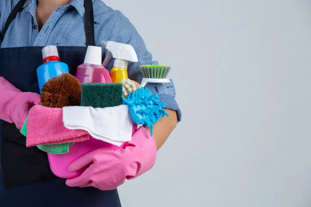 Maid service: Person in pink gloves holds cleaning supplies. Professional cleaner with spray bottles and sponges. Cleaning services in Washington DC.