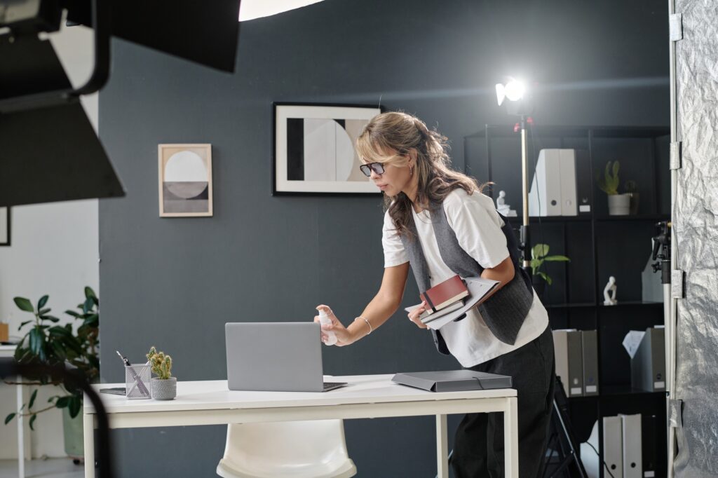 Woman sanitizing laptop in studio. Professional photography setup. Keeping equipment clean for headshots and portraits. Washington DC.