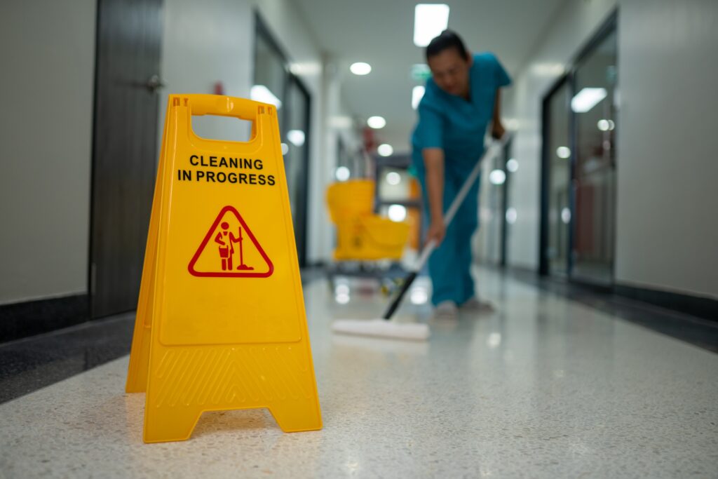 Cleaning in progress sign with worker mopping floor. Commercial cleaning services ensure safety and hygiene in Washington DC.