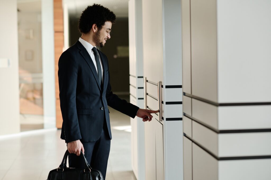 Man in suit presses elevator button, holding bag. Office building interior, Washington DC. Commercial real estate for lease or rent.
