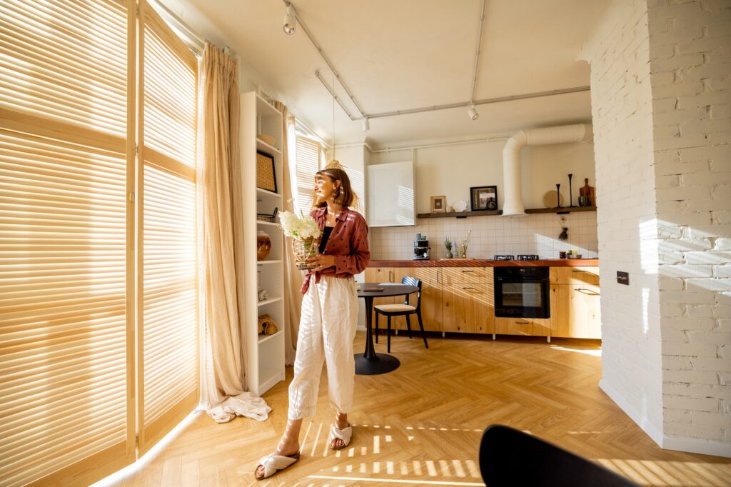Woman holding flowers in a bright, modern kitchen with herringbone wood floors and white brick. Interior design inspiration in Washington DC.