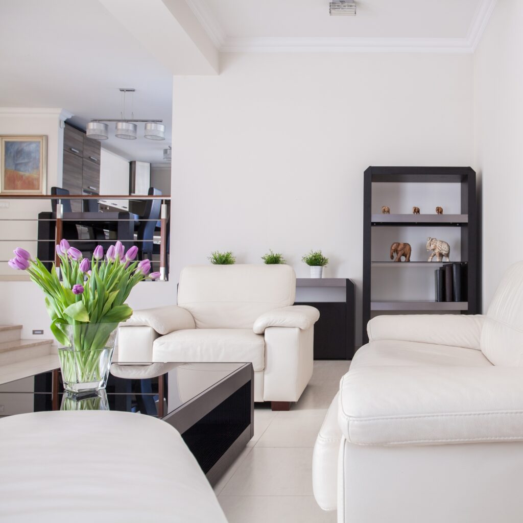 Modern living room interior design with white leather furniture, black accents, and a vase of purple tulips in Washington DC.